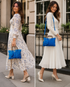 A split-screen lifestyle image showing a woman in two different outfits carrying a bright blue textured handbag. On the left, she wears a cream floral midi dress and holds the blue bag.

